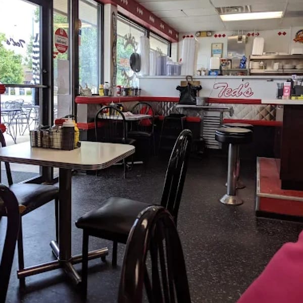 Interior of Ted's Coney Island diner with red and white decor, tables, and counter seating.